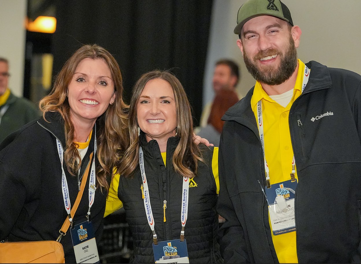 Three KOA attendees wearing convention badges, smiling together